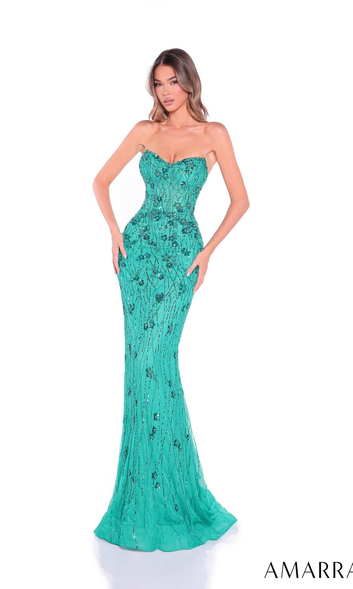 A woman wears the Amarra 89171 long prom dress in turquoise. This strapless, floor-length gown features decorative embellishments and a fitted silhouette, perfect for special evenings. She poses against a white background.